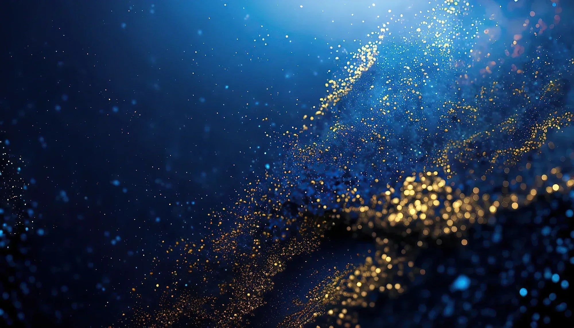 Abstract blue background with shimmering gold particles and glittering light effects